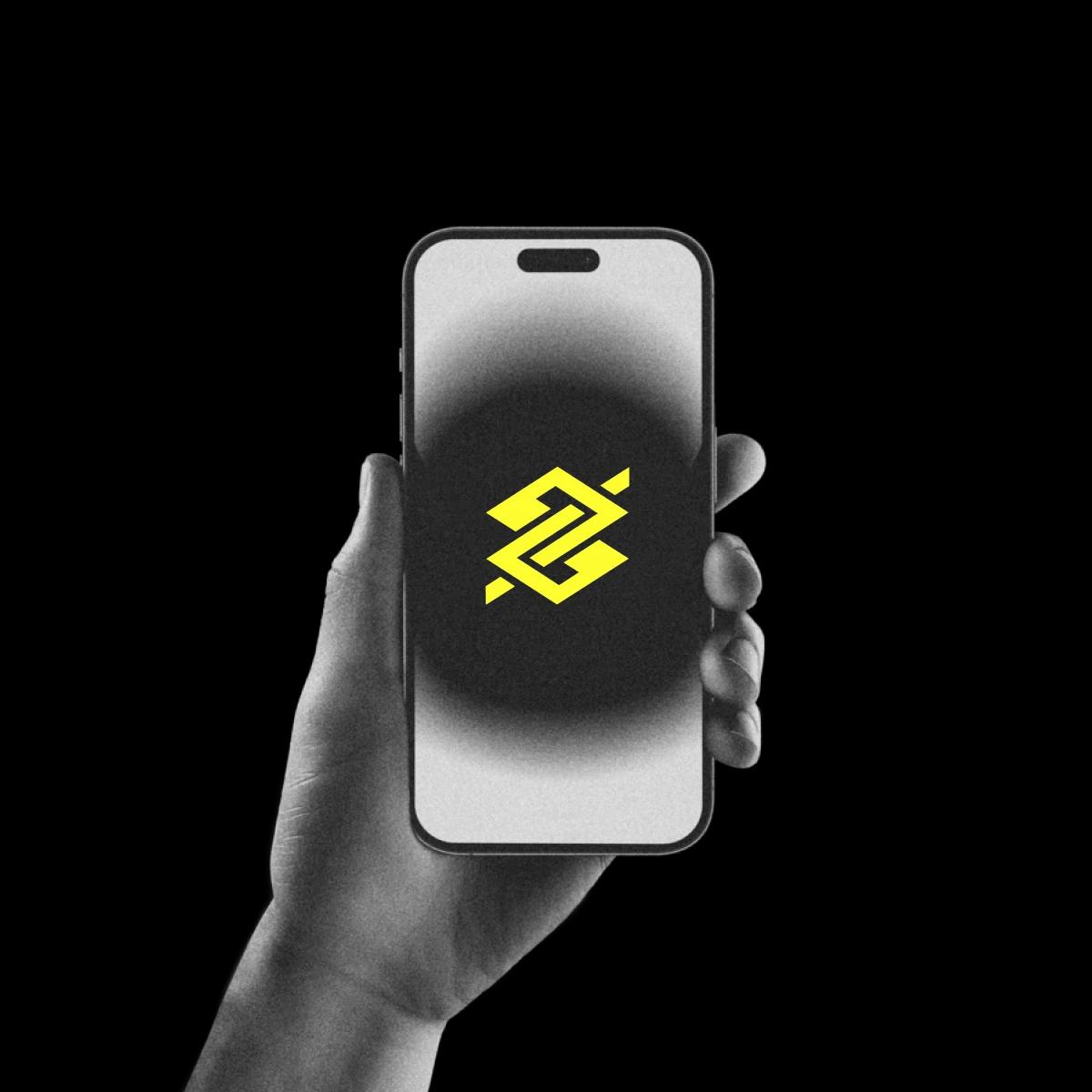 Mão segurando smartphone com logo do banco do brasil na tela